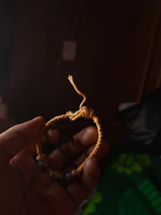 Artesano tejiendo una pulsera de macramé con piedras naturales coloridas a la luz cálida.