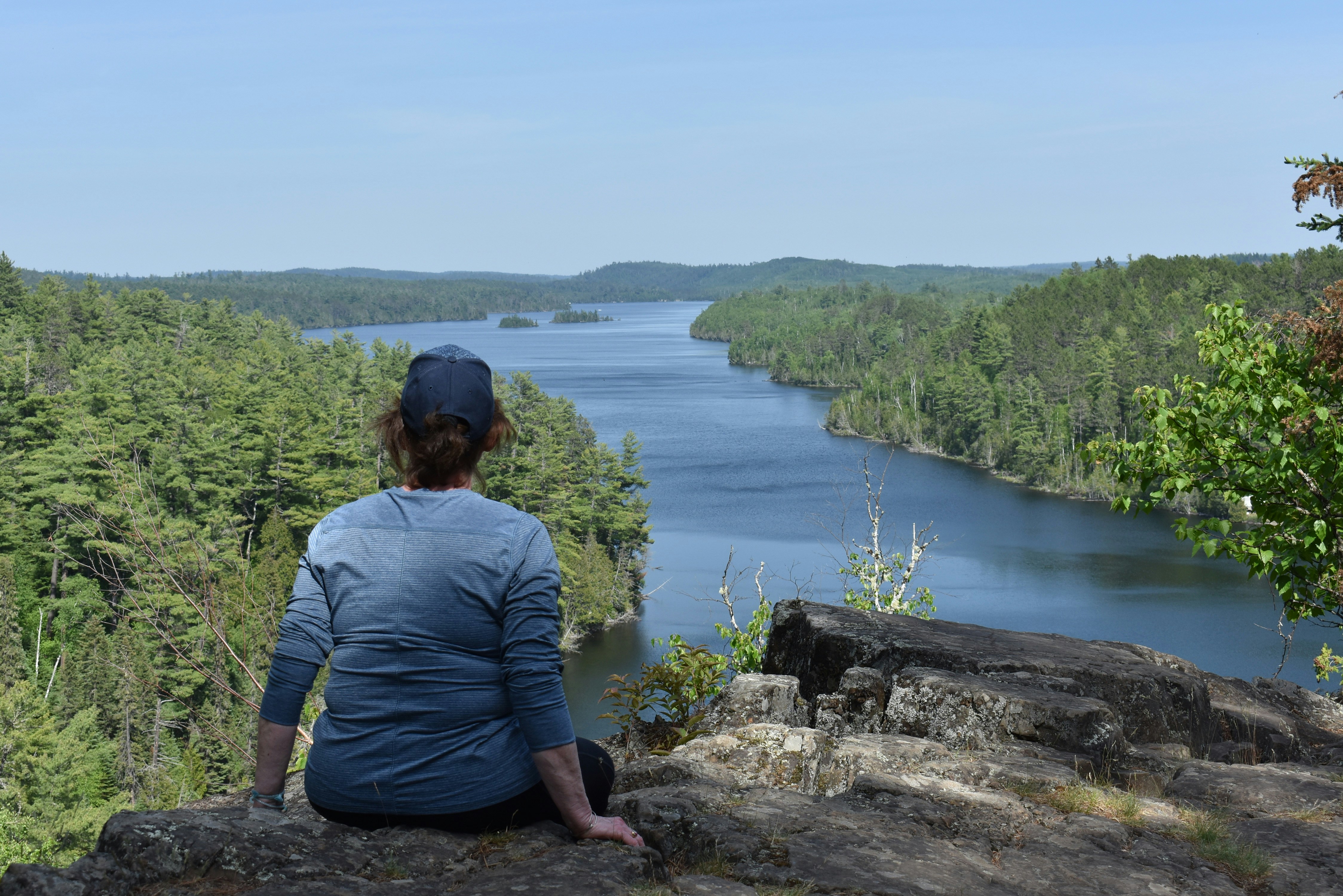 A woman sitting on a rock looking out over a river photo – Free Woman ...