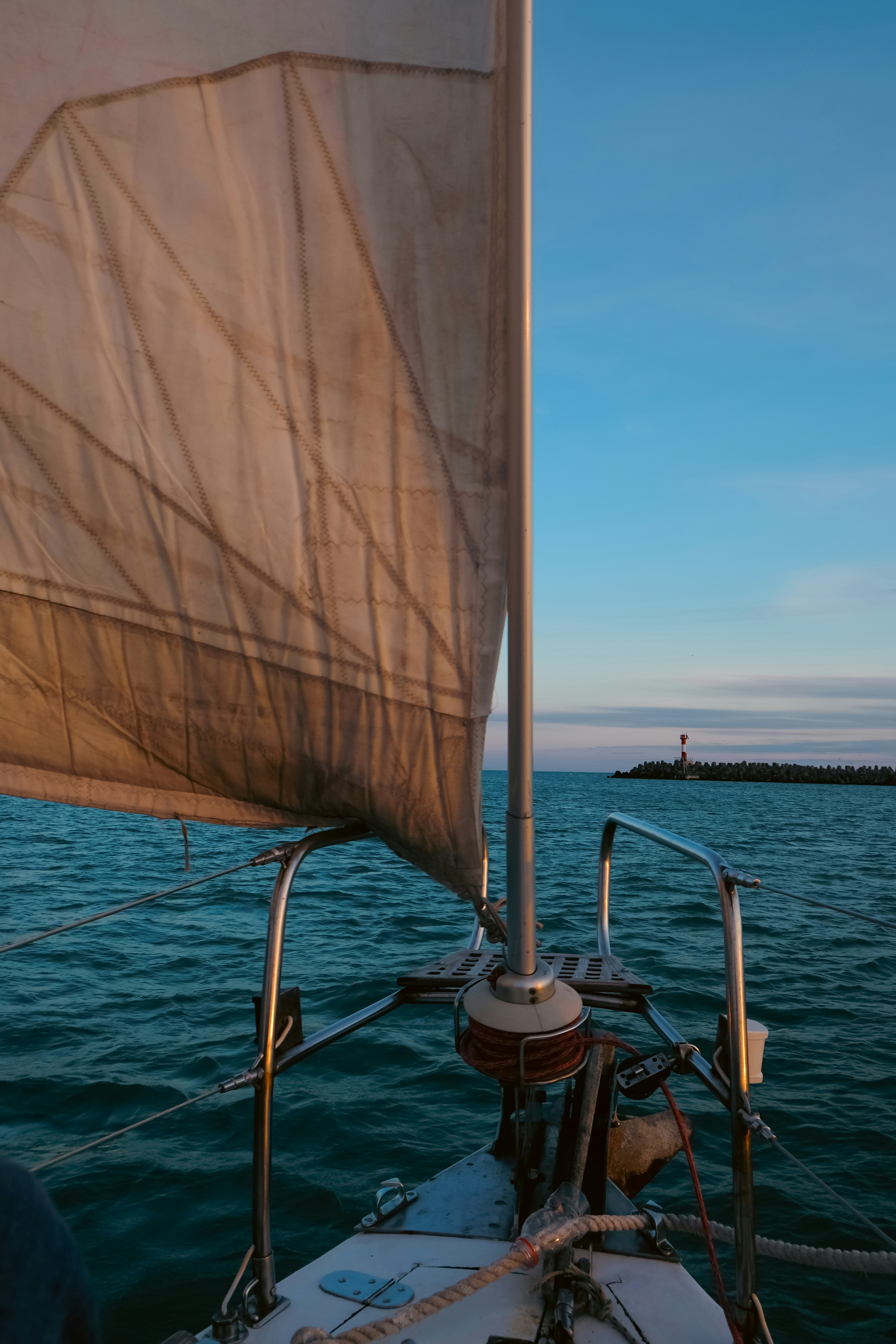 a sailboat with a white sail on a body of water