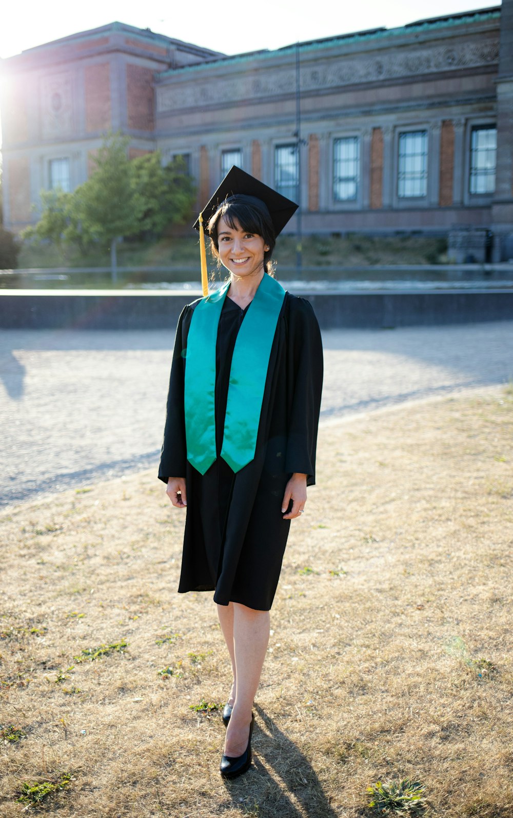 a woman in a graduation gown standing in a field
