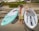 Smiling man standing next to his paddle board on a sunny beach