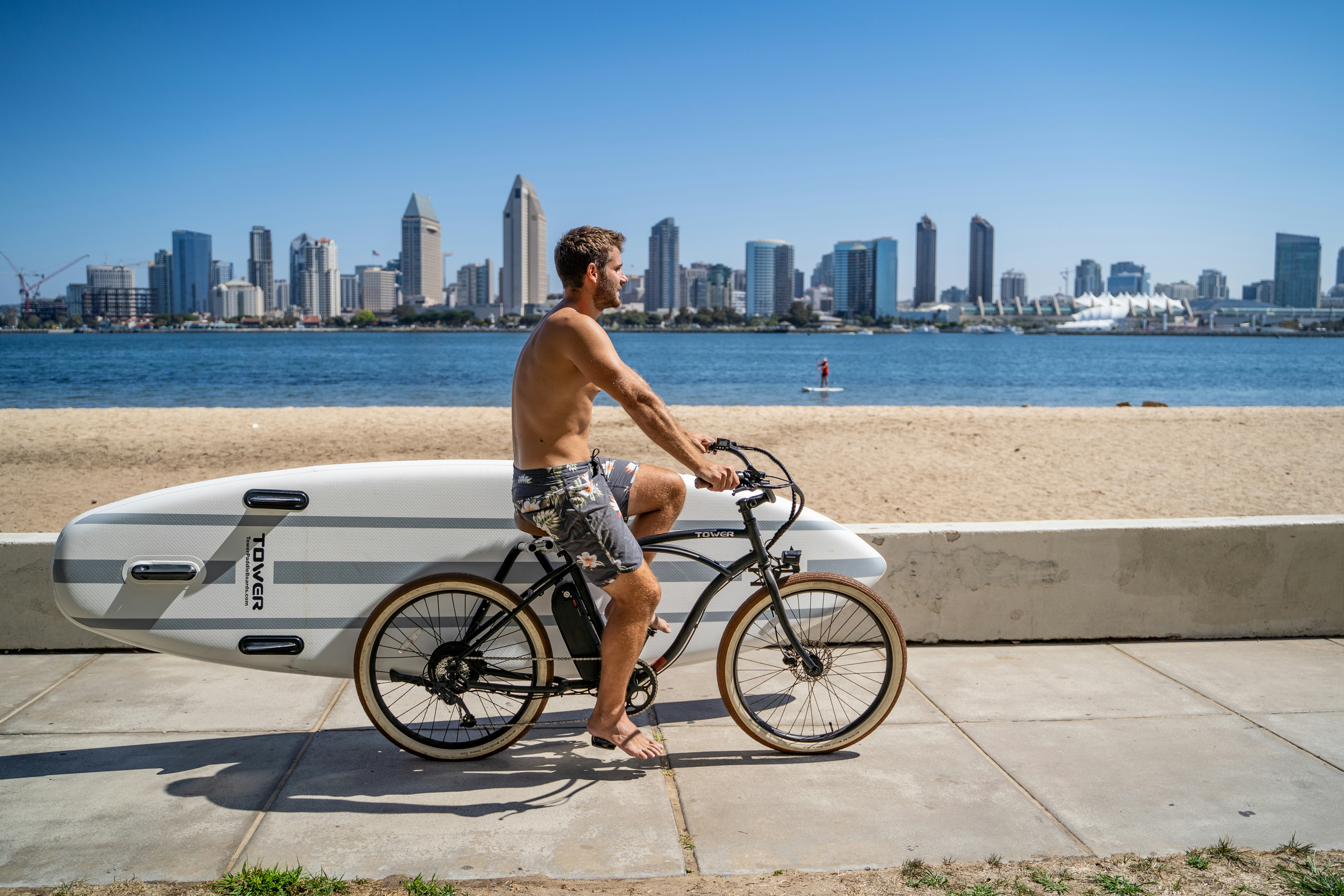 a man riding a bike with a surfboard strapped to the back of it