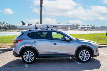 Happy tourists loading luggage into a spacious rental SUV in a sunny city setting.