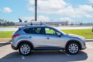 A family loading gear into a spacious SUV on a sunny day.