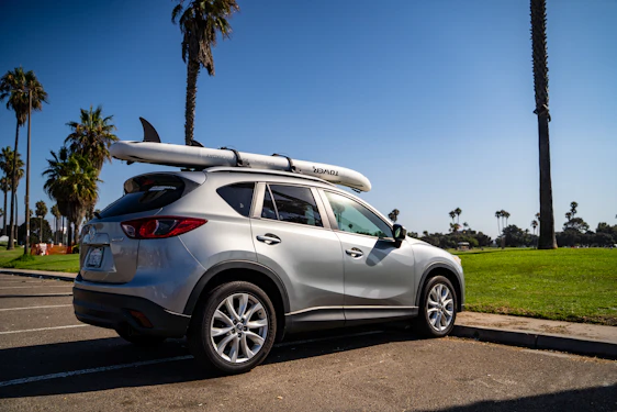 A friendly customer picking up a shiny SUV at the airport rental desk under clear skies.