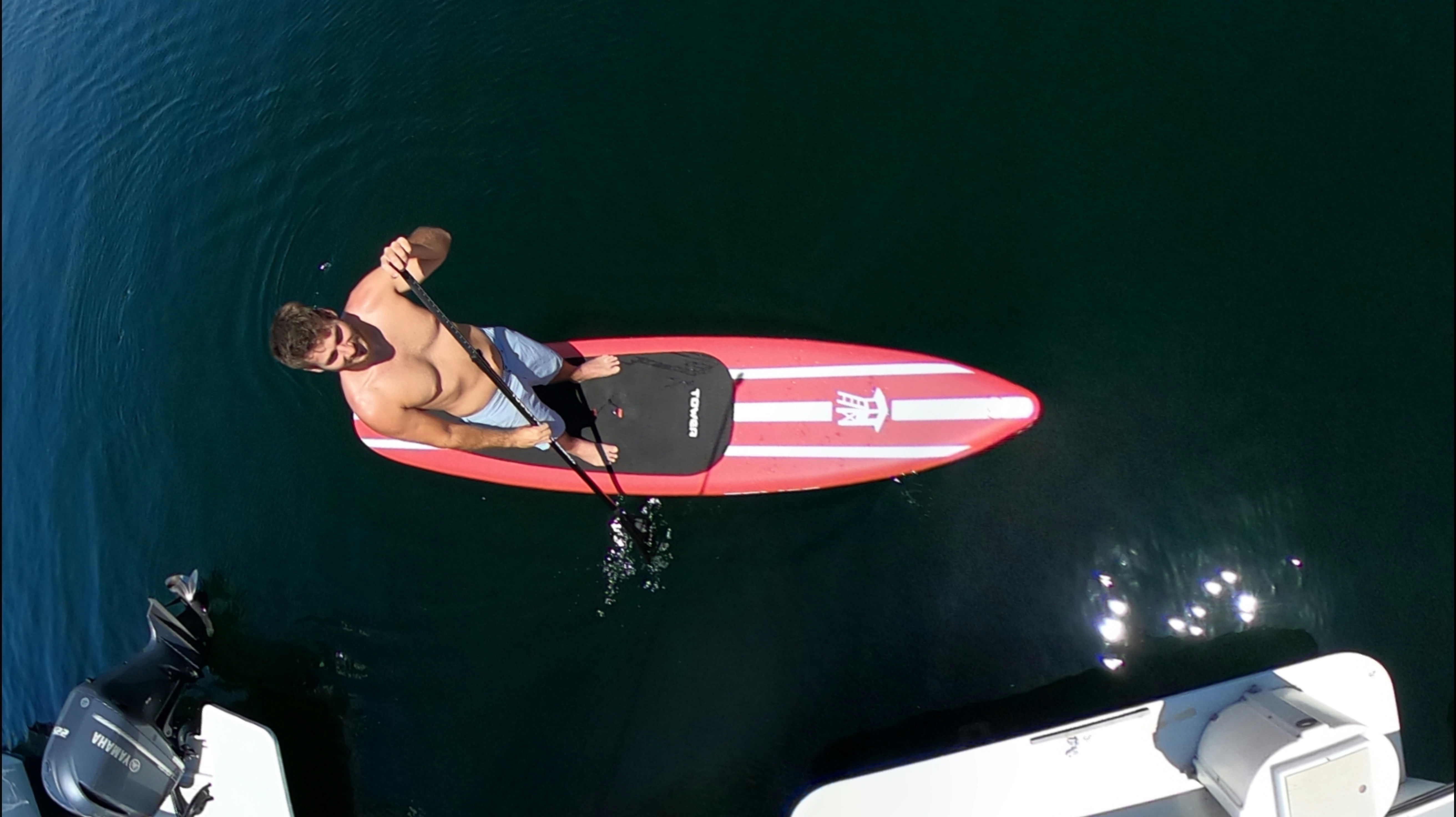a man riding a red surfboard on top of a body of water