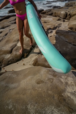 a woman in a pink bikini holding a blue surfboard
