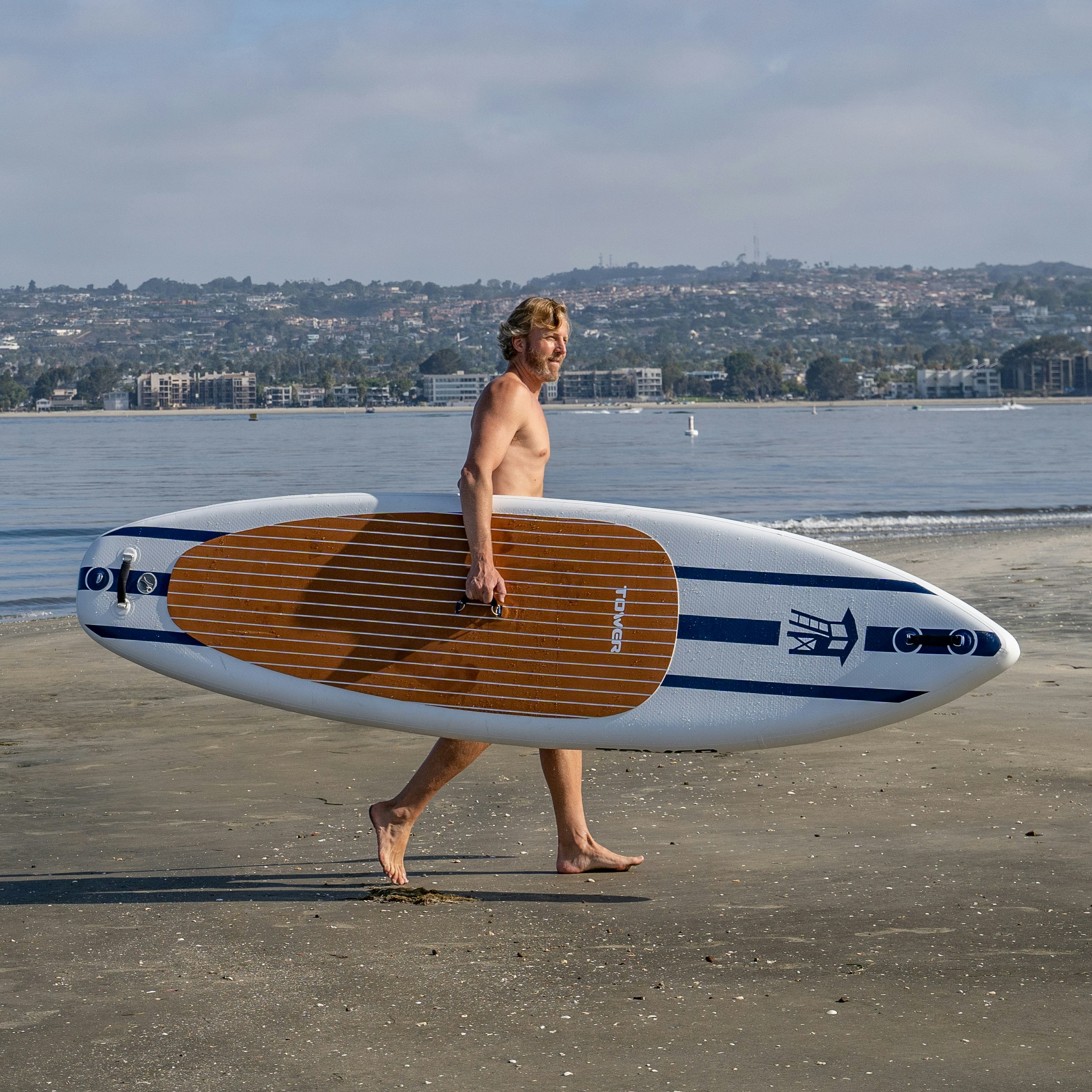 a man walking on a beach holding a surfboard