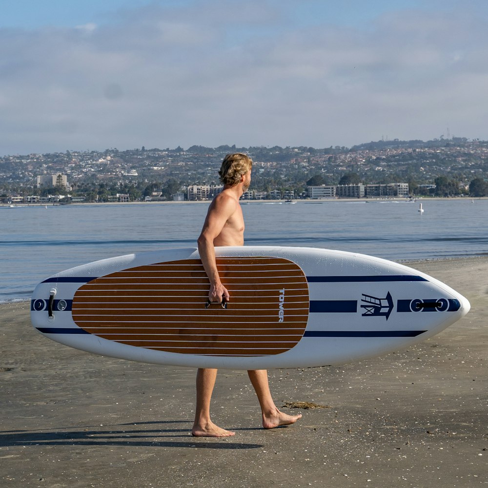 a man walking on a beach holding a surfboard
