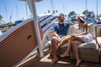 A candid shot of a couple laughing aboard a sailboat as the soft-focus ropes flutter in the breeze.