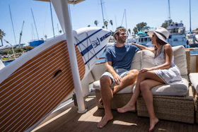 A candid shot of a couple laughing aboard a sailboat as the soft-focus ropes flutter in the breeze.