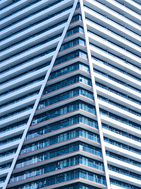 A modern high-rise building characterized by a sharp, angular design. The structure features numerous rows of windows, creating a pattern of glass and concrete. The prominent V-shape adds a dynamic and futuristic aesthetic.