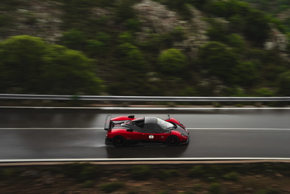 a red sports car driving down a wet road