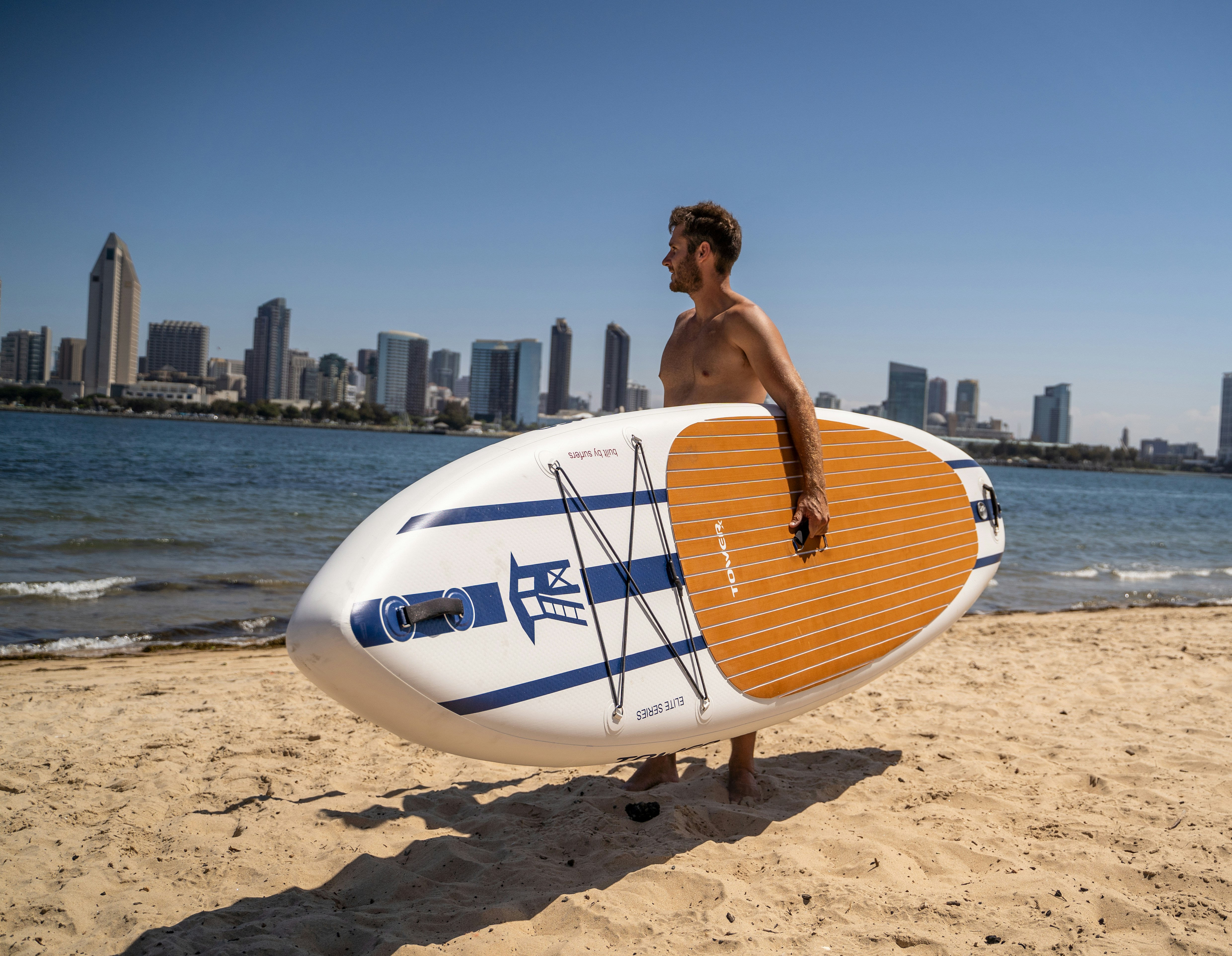 a man standing on a beach holding a surfboard