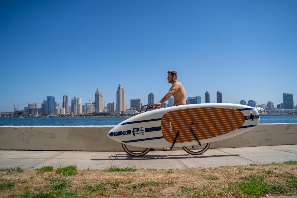 a man riding a bike with a surfboard on it