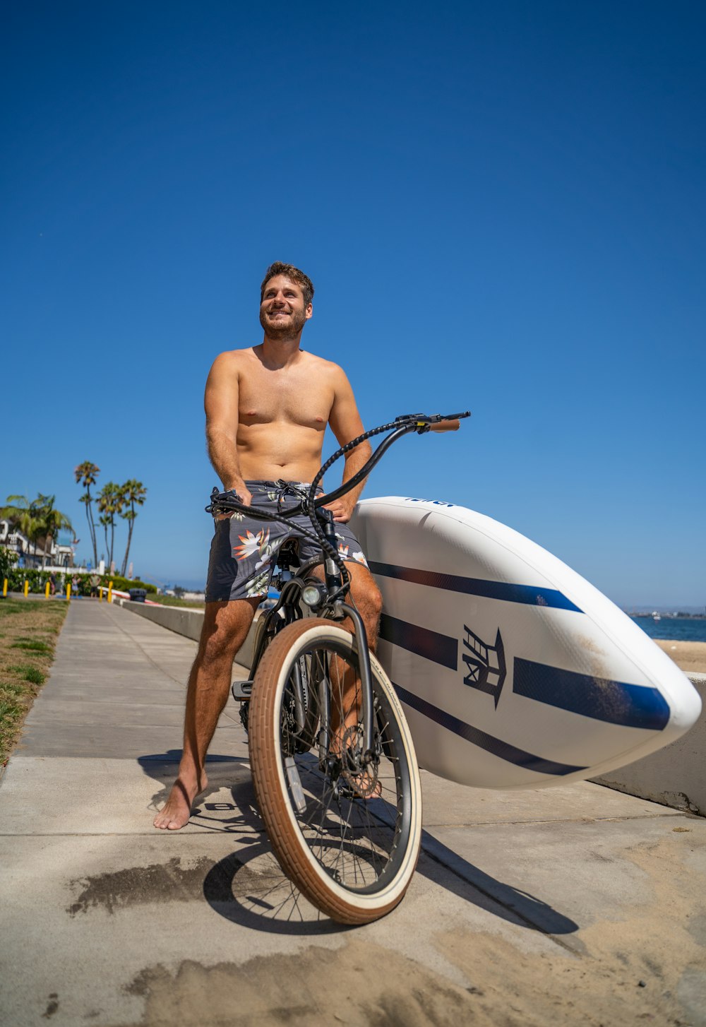 a man sitting on a bike next to a surfboard