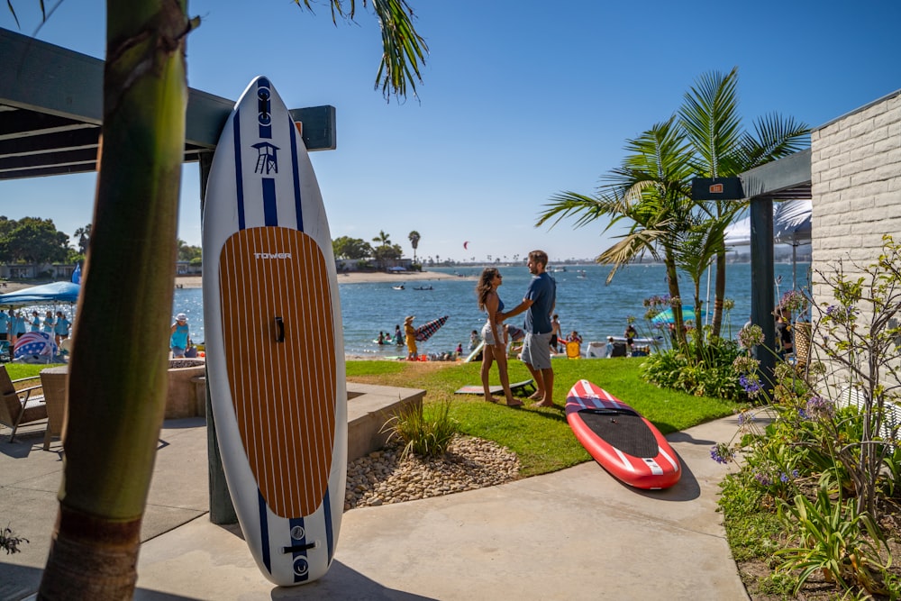 a man standing next to a red and white surfboard