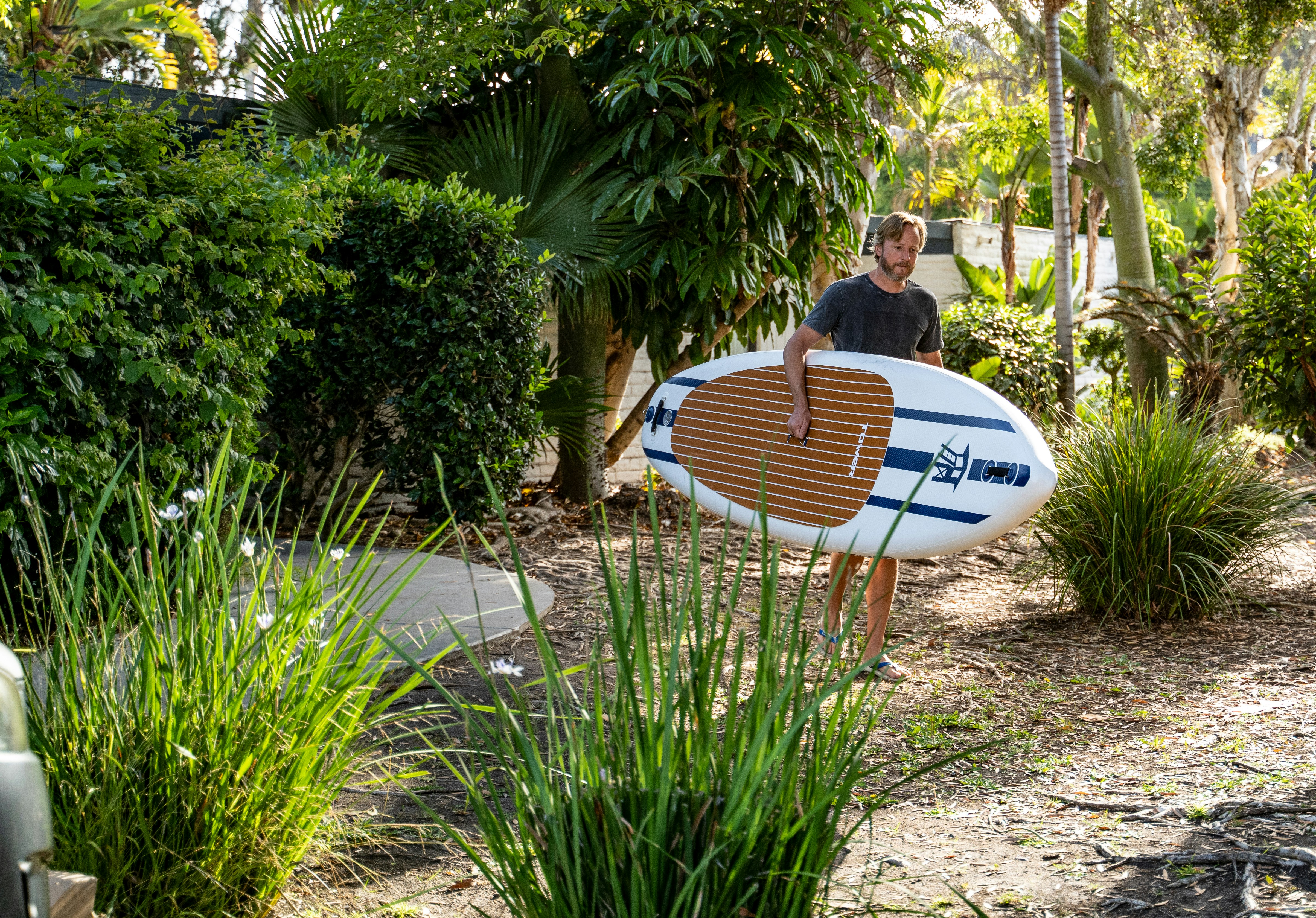 a man holding a surfboard in a garden