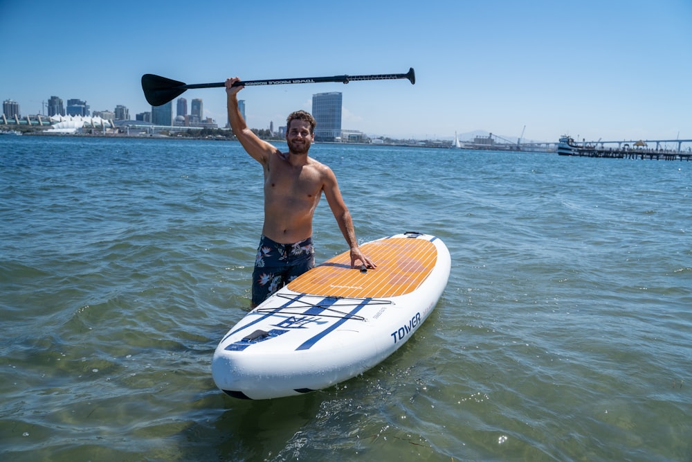 a man standing on a surfboard holding a paddle