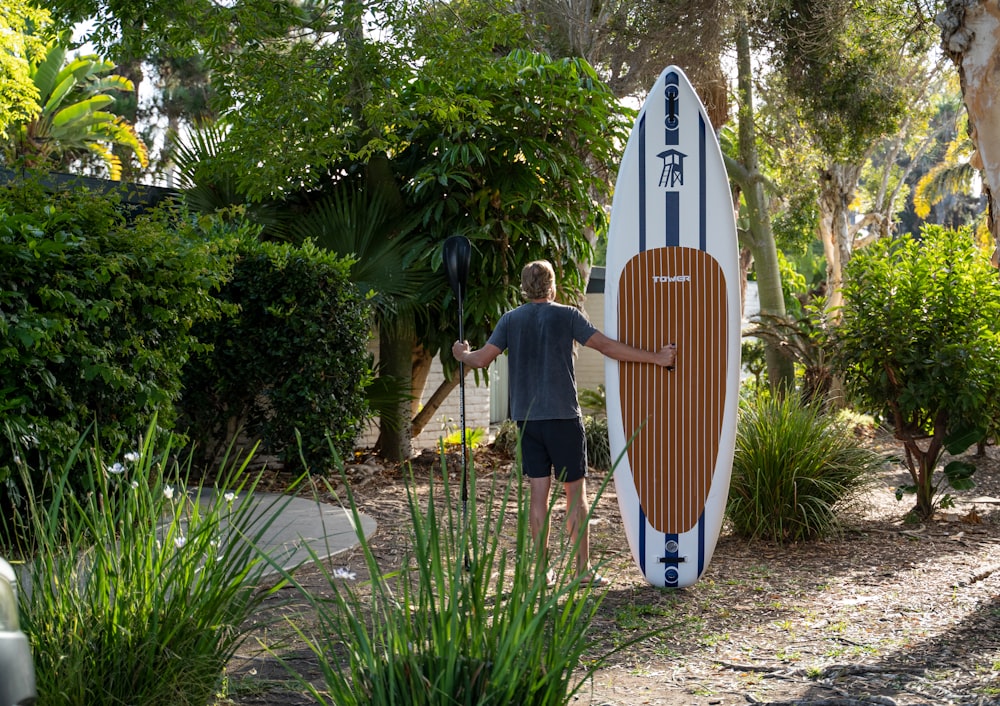 a man standing next to a surfboard in a garden