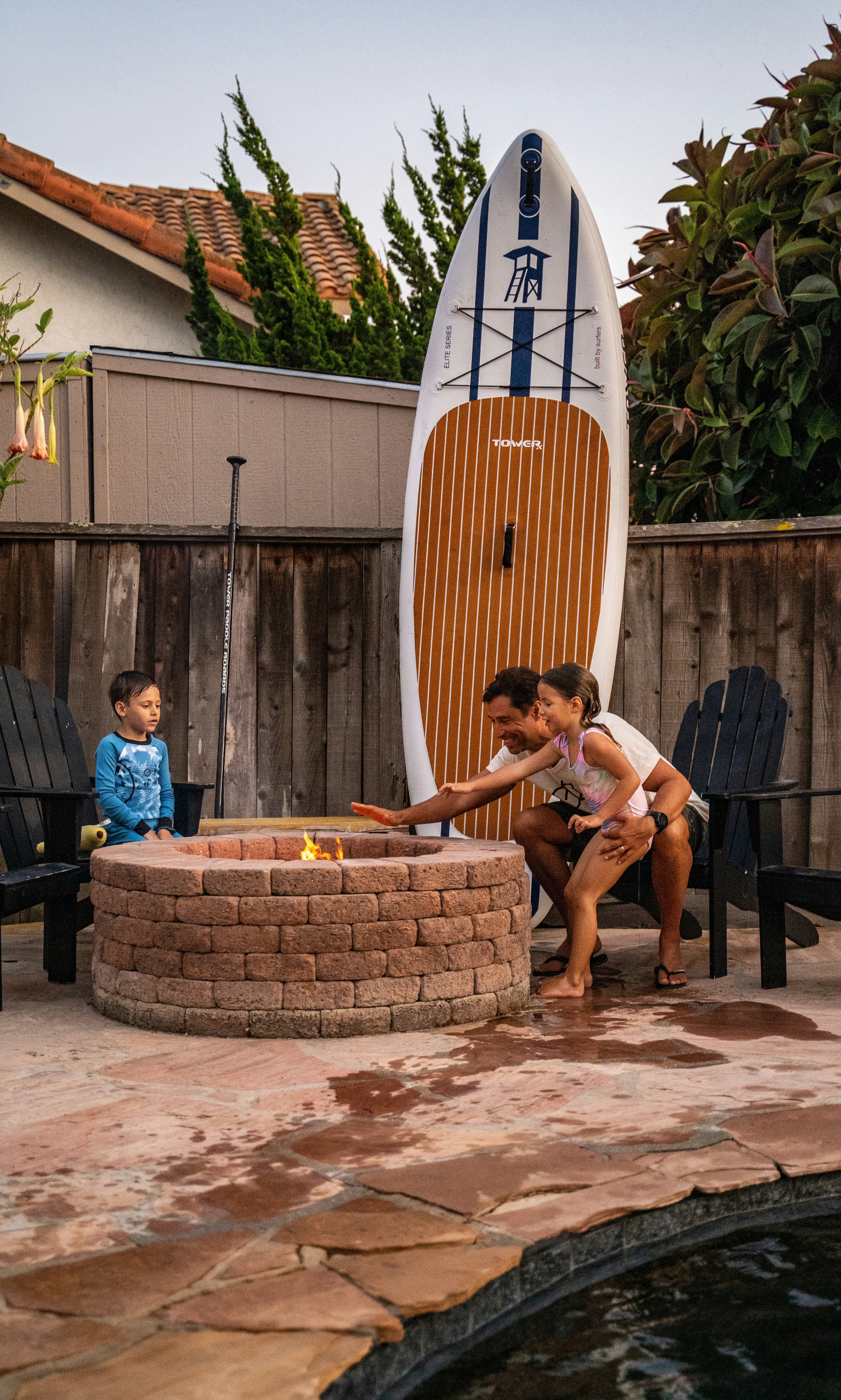a boy and a girl playing around a fire pit