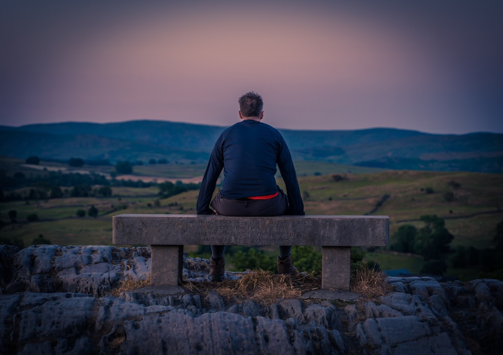 a man sitting on a bench overlooking a valley