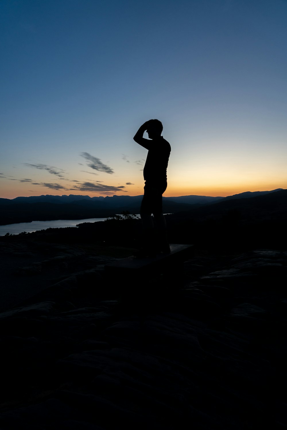 a man standing on top of a hill next to a body of water