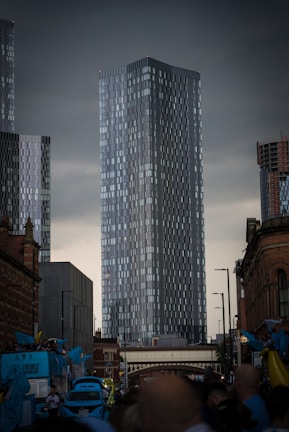 a group of people walking down a street next to tall buildings