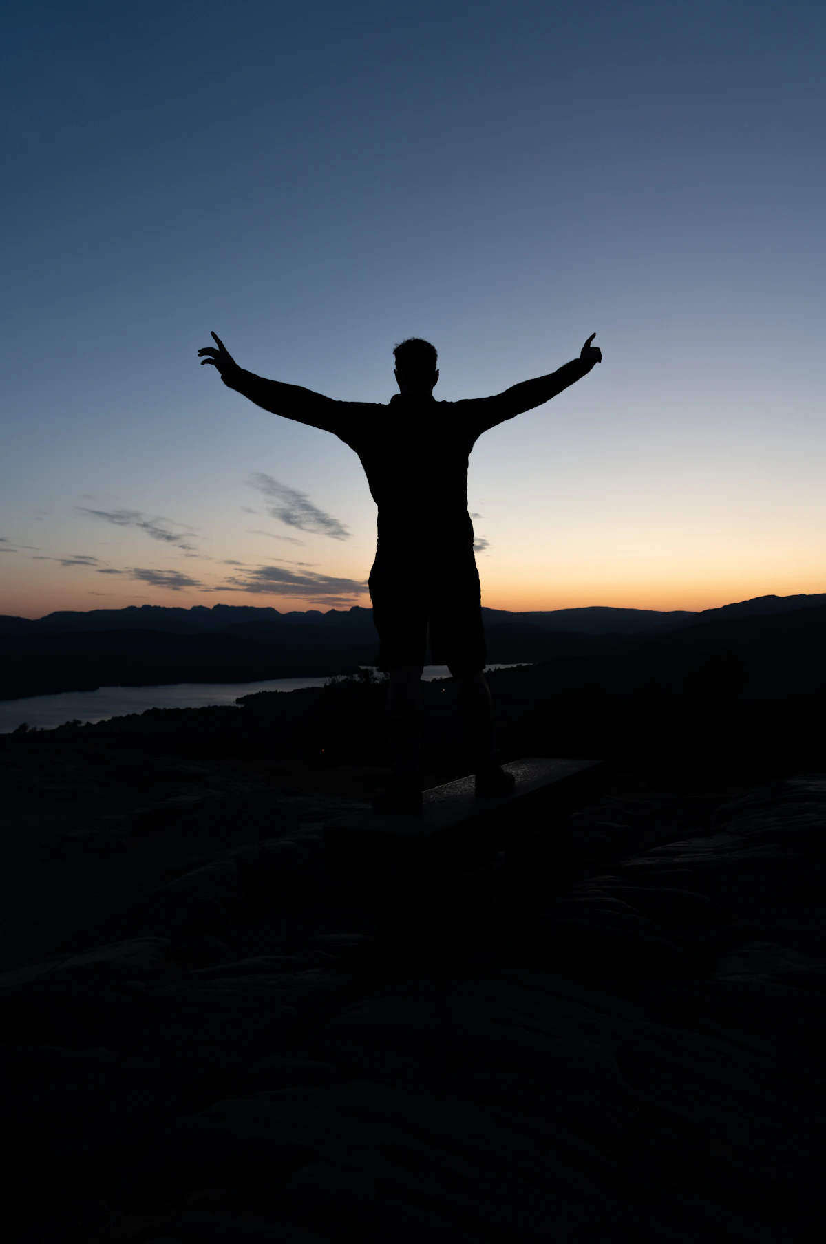 Person standing tall and grounded outdoors, arms extended, symbolizing steady upright posture in Tadasana