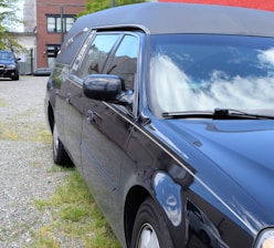 An elegant hearse parked outside a modern funeral home at dusk.