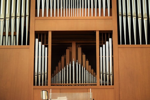 A large pipe organ with vertical silver pipes arranged symmetrically against a wooden backdrop, creating a harmonious and structured pattern.