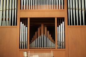 A large pipe organ with vertical silver pipes arranged symmetrically against a wooden backdrop, creating a harmonious and structured pattern.