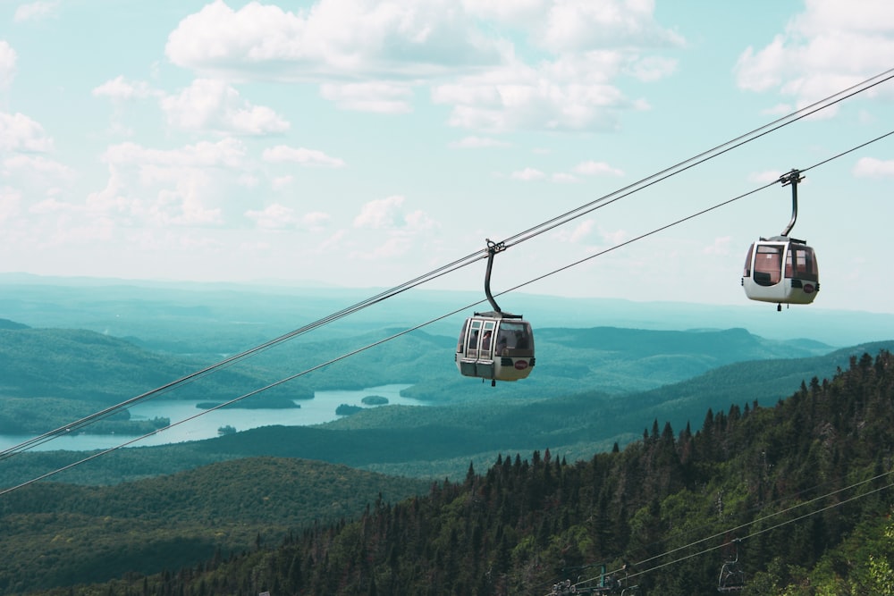 a couple of gondolas hanging over a lush green hillside