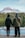two people standing on a dock looking at a lake