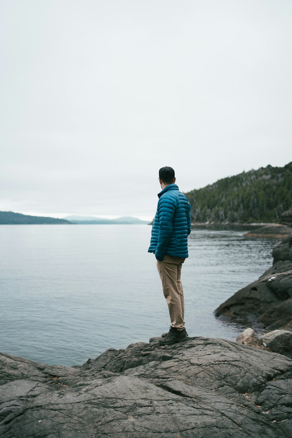 a man standing on top of a rock next to the ocean