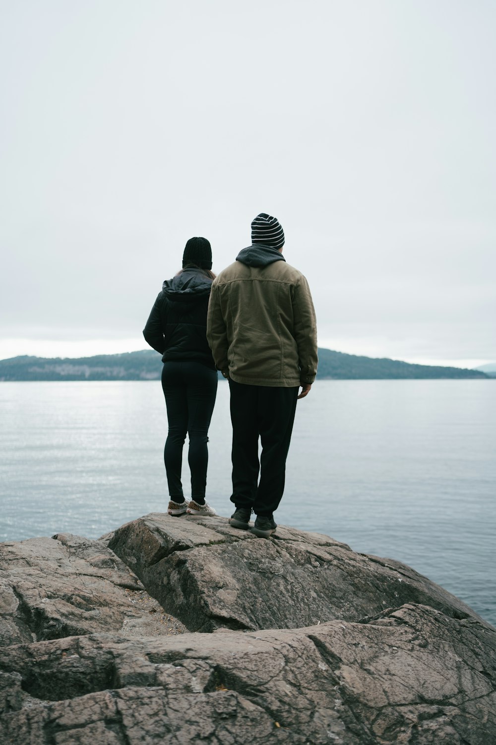 a couple of people standing on top of a rock