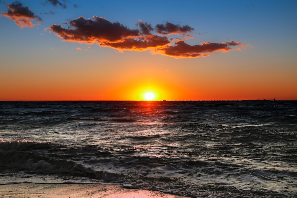 a sunset over the ocean with a boat in the distance