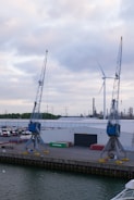 a dock with two cranes and a boat in the water