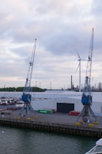 a dock with two cranes and a boat in the water