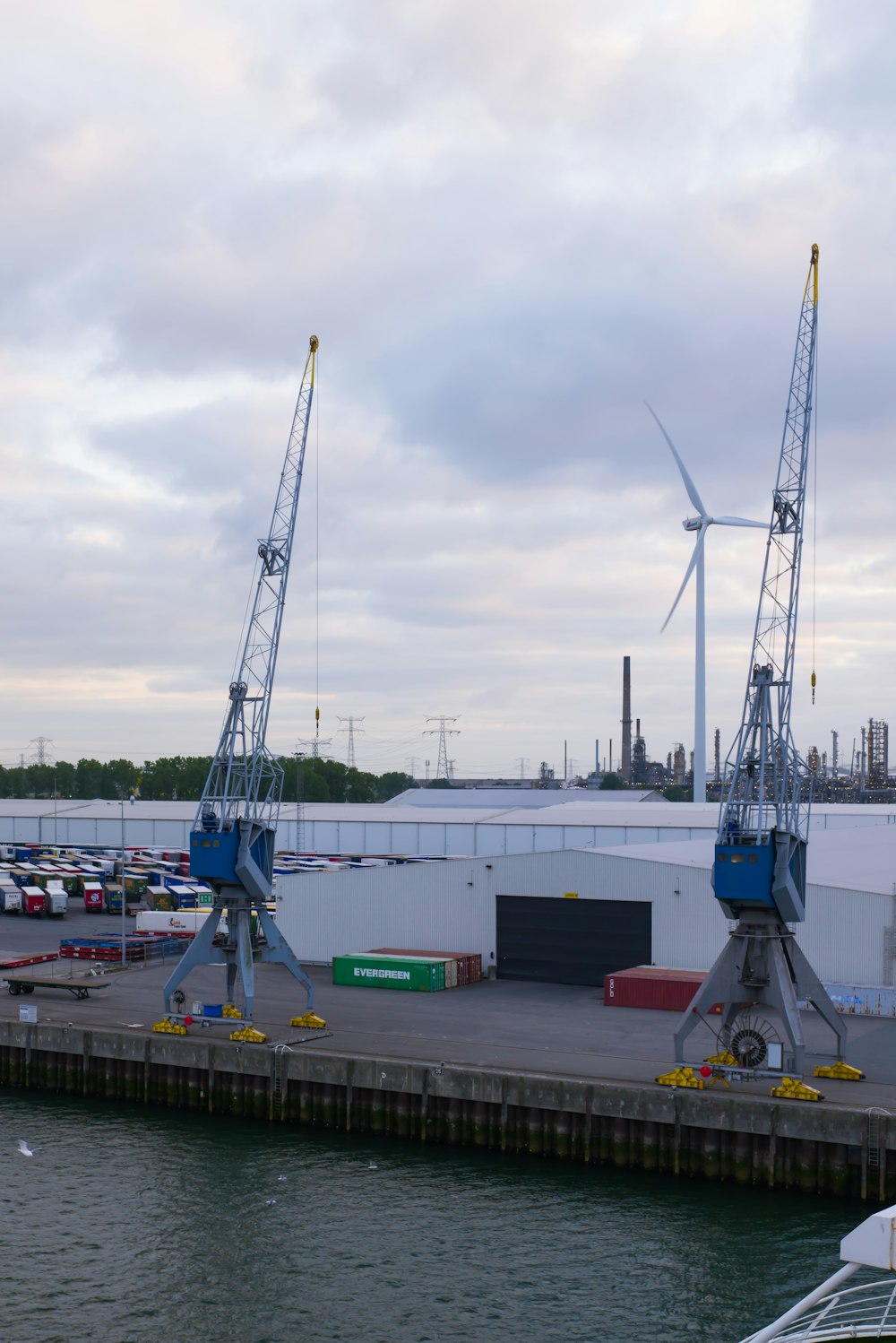 a dock with two cranes and a boat in the water