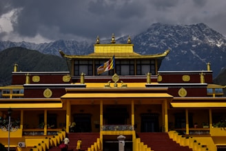 a yellow and red building with mountains in the background
