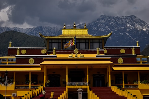 a yellow and red building with mountains in the background