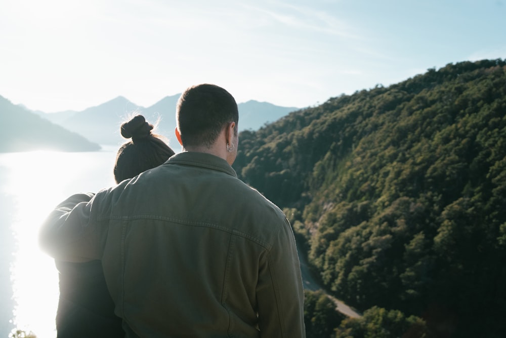 a man holding a small bird while standing on top of a mountain