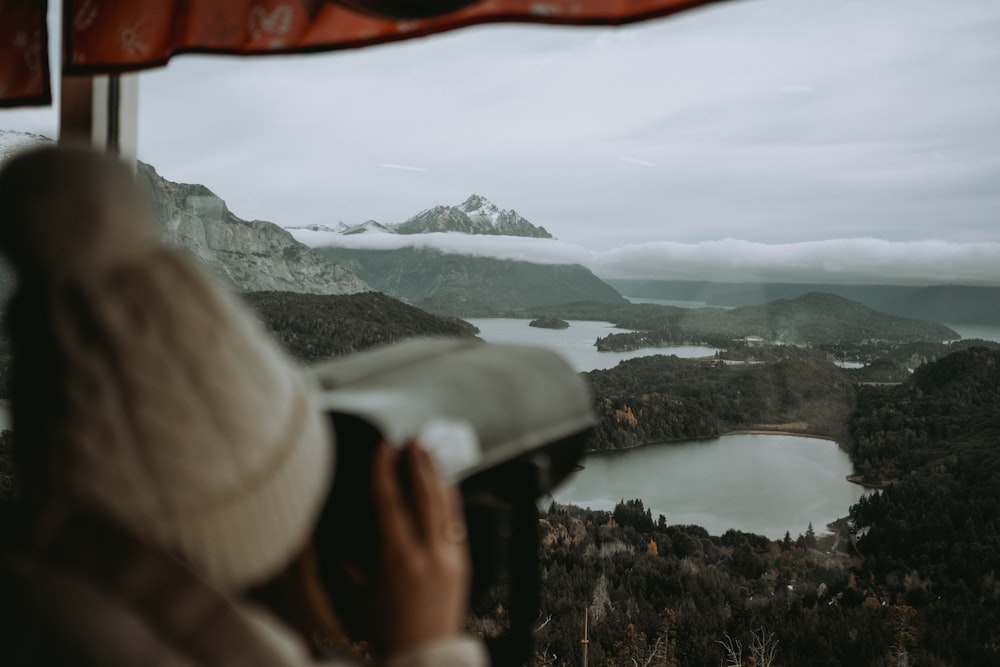 a person looking out a window at a lake