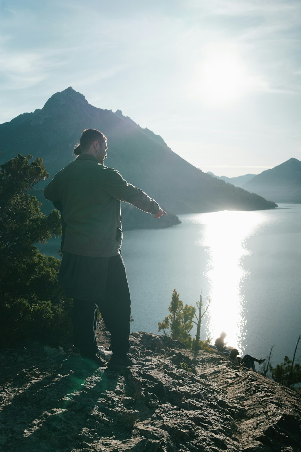 a man standing on top of a mountain next to a lake