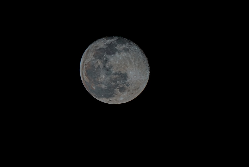 a full moon is seen in the dark sky