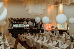 a dining room filled with tables and white balloons