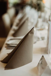 Delicate linen napkins folded with precision beside polished bronze cutlery in warm lighting.