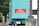 The image displays an industrial setup with a teal-colored equipment box featuring a red sign that reads 'Diesel No Smoking or Open Flames'. Surrounding the box is a black chain-link fence, brick pillars, and some greenery is visible in the background.
