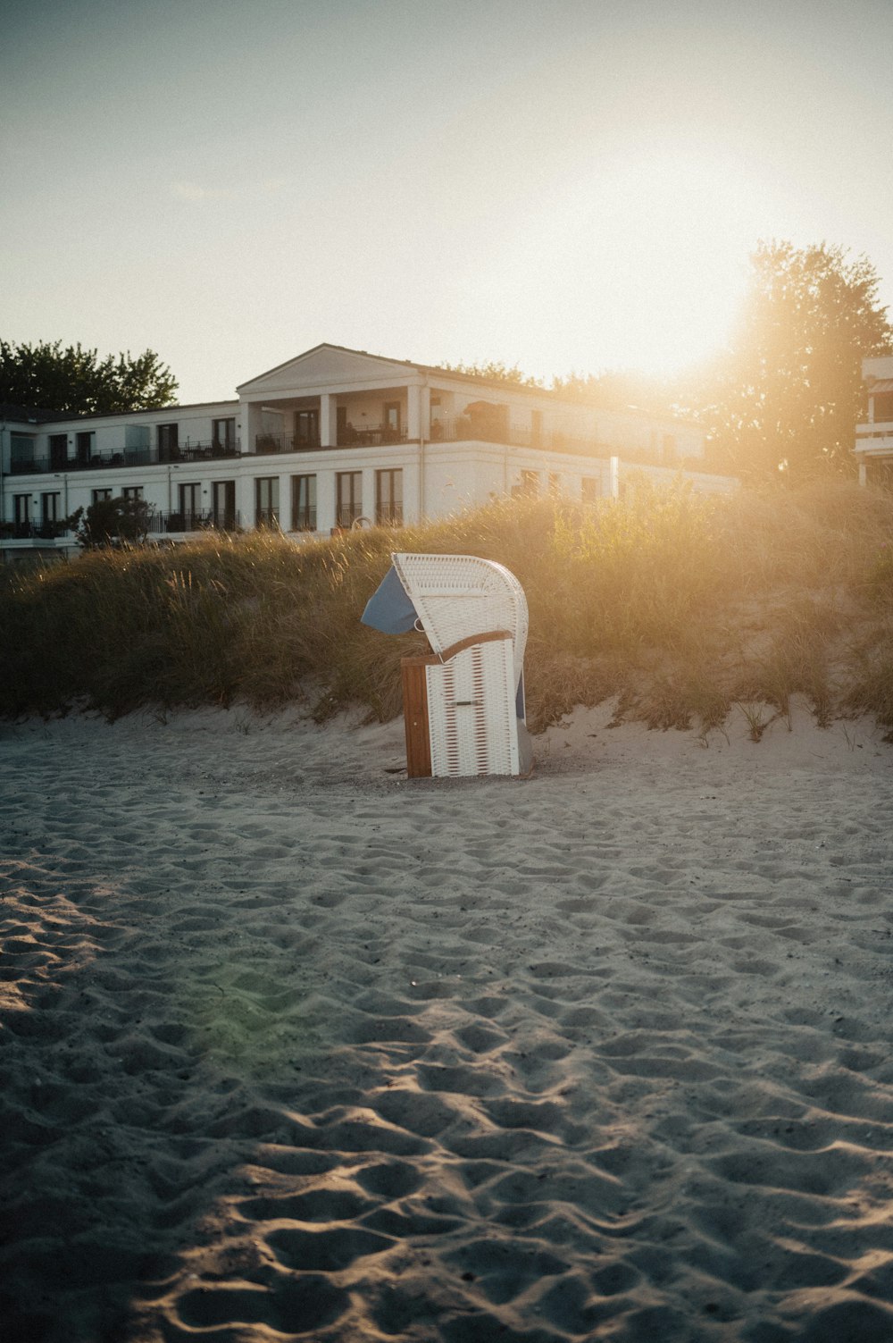 a white beach chair sitting on top of a sandy beach